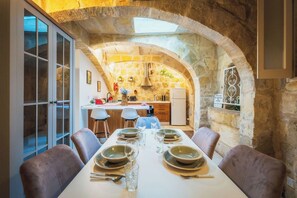 Un comedor con un arco de piedra, una cocina al fondo y un cartel que prohíbe fumar.