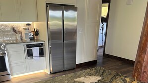 Una cocina con encimera de mármol, electrodomésticos de acero inoxidable y armarios blancos.