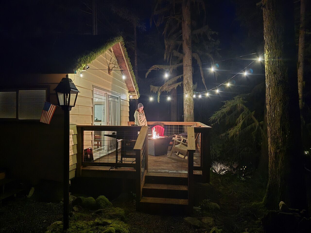 A house with a deck, a fire pit, and string lights.