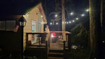 A house with a deck, a fire pit, and string lights.