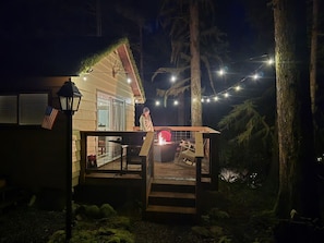 A house with a deck, a fire pit, and string lights. - Moss Top Cabin-off grid living moss roof cabin in the woods (Marblemount)