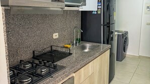 Een moderne keuken met granieten aanrechtbladen, roestvrijstalen apparatuur en houten kastjes.