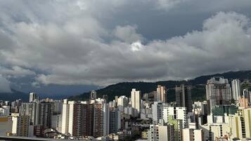 Un paisaje urbano con rascacielos, cielo despejado y una cadena montañosa distante.