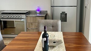 A modern kitchen with a built-in oven, a refrigerator, and a dining area with a table set for two. - Exclusive apartment in Andares, the #1 in Guadalajara - Swimming pool - Jacuzzi - AC (Zapopan)