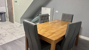Een eethoek met een houten tafel en vier grijs beklede stoelen.