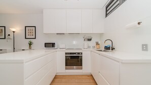 A modern kitchen with white cabinetry, a microwave, a toaster, and a built-in oven. - Cosy Urban Escape near Sydneys Top Attractions (Ultimo)