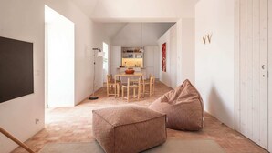 A modern, minimalist living space with a dining area, a large window, and a cozy seating area with two bean bags. - Danna Portuguese Design House nº 10 (Tavira)