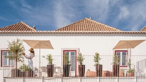 A building with a tiled roof, a balcony with a railing, and potted plants. - Danna Portuguese Design House nº 10 (Tavira)