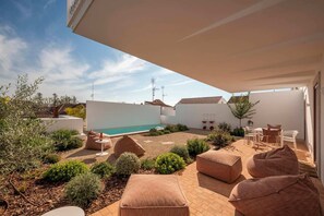 Un patio moderno al aire libre con piscina, zonas de estar y vistas despejadas del vecindario.