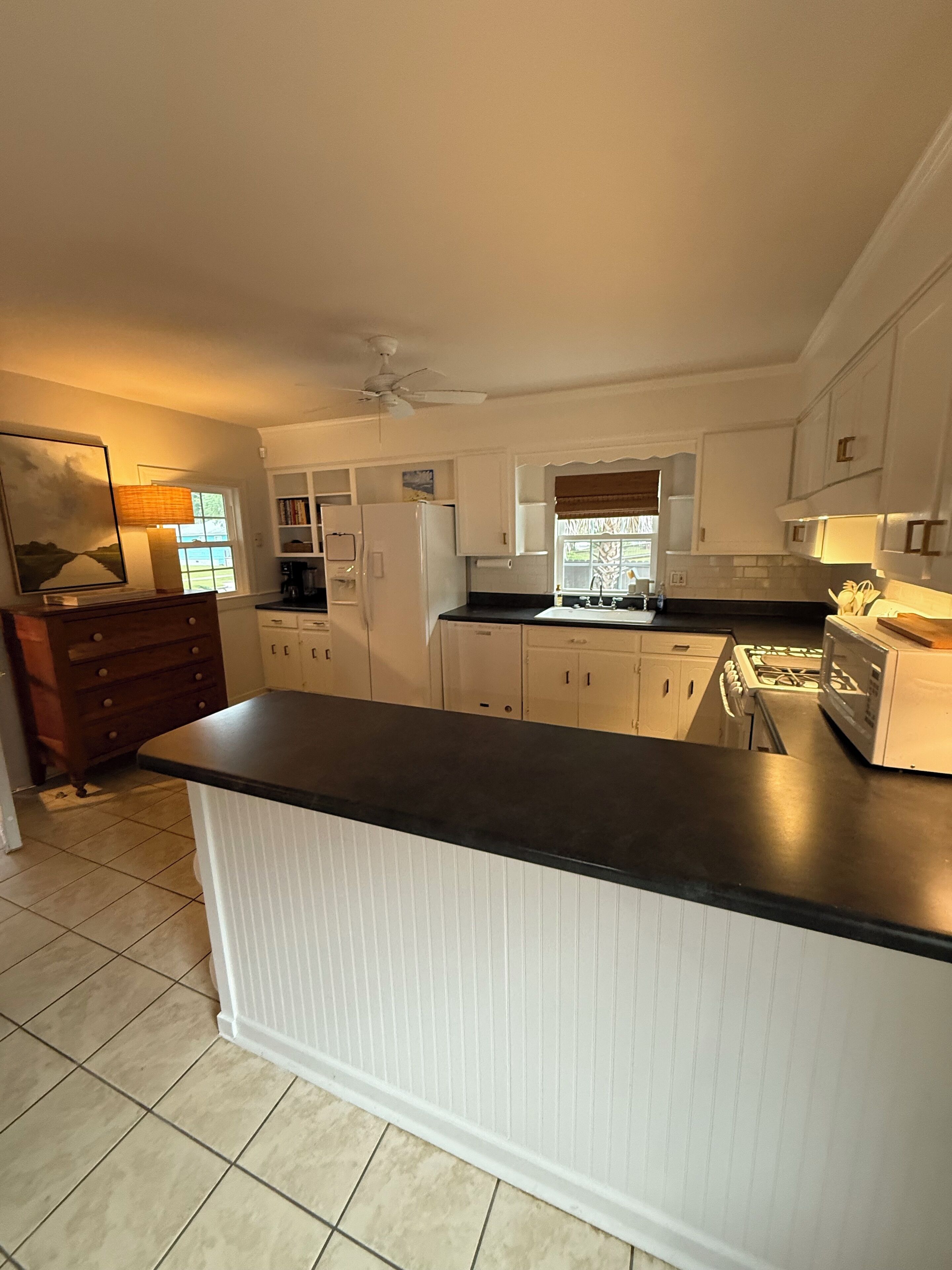 A kitchen with white cabinets, a black countertop, and a window with a view of the outdoors.