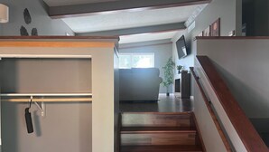 A staircase with wooden steps and a handrail, leading to a living area with a sofa and a television. - A cozy and warm 3 bedroom retreat in the heart of the Midwest (Lincoln)