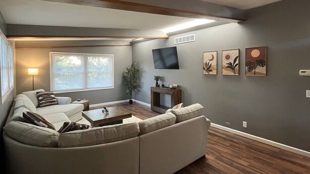 A living room with a sofa, coffee table, and a flat-screen TV mounted on the wall. - A cozy and warm 3 bedroom retreat in the heart of the Midwest (Lincoln)