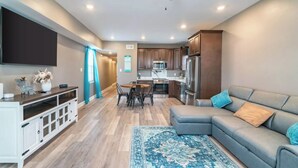 A modern living room with a grey sectional sofa, a flat-screen TV, and a ceiling fan.
