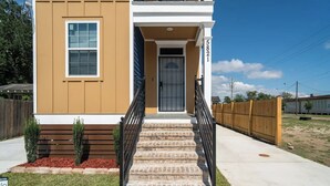 A two-story house with a front entrance, a staircase with black railings, and a mailbox.