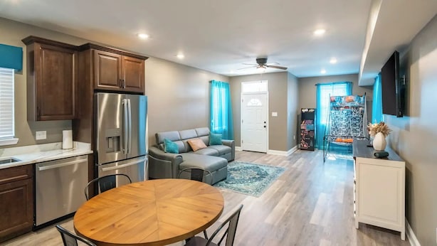 A modern kitchen with stainless steel appliances, a dining table, and a gray sofa.