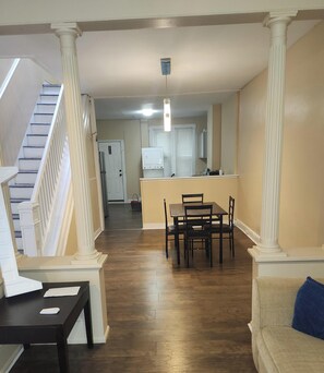 A spacious living area with a staircase, a dining table with chairs, a kitchen area, and a light fixture on the ceiling. - 3-bedroom townhome in superb Baltimore with AC (Baltimore)