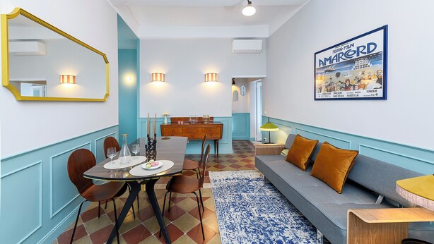 Un espace repas moderne avec une table en bois, des chaises et un tapis à motifs bleus.