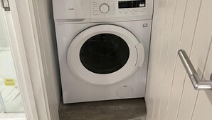 Eine kompakte Waschmaschine mit Bedienfeld, einem Wäscheständer und einer Tür.
