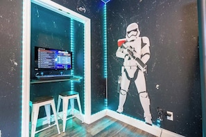 A room with a Star Wars-themed wall, a television, and two stools. - Near Disney Premium Location Coral Cay Resort (Kissimmee)