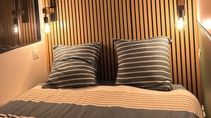 Un dormitorio con cabecera de listones de madera, dos lámparas de noche y ropa de cama a rayas.