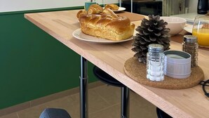 Un desayuno con hogaza de pan, piña, salero y pimentero, y un vaso de zumo de naranja sobre una mesa de madera.