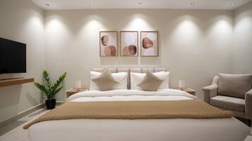 A modern bedroom with a large bed, bedside tables, a TV, and a plant.