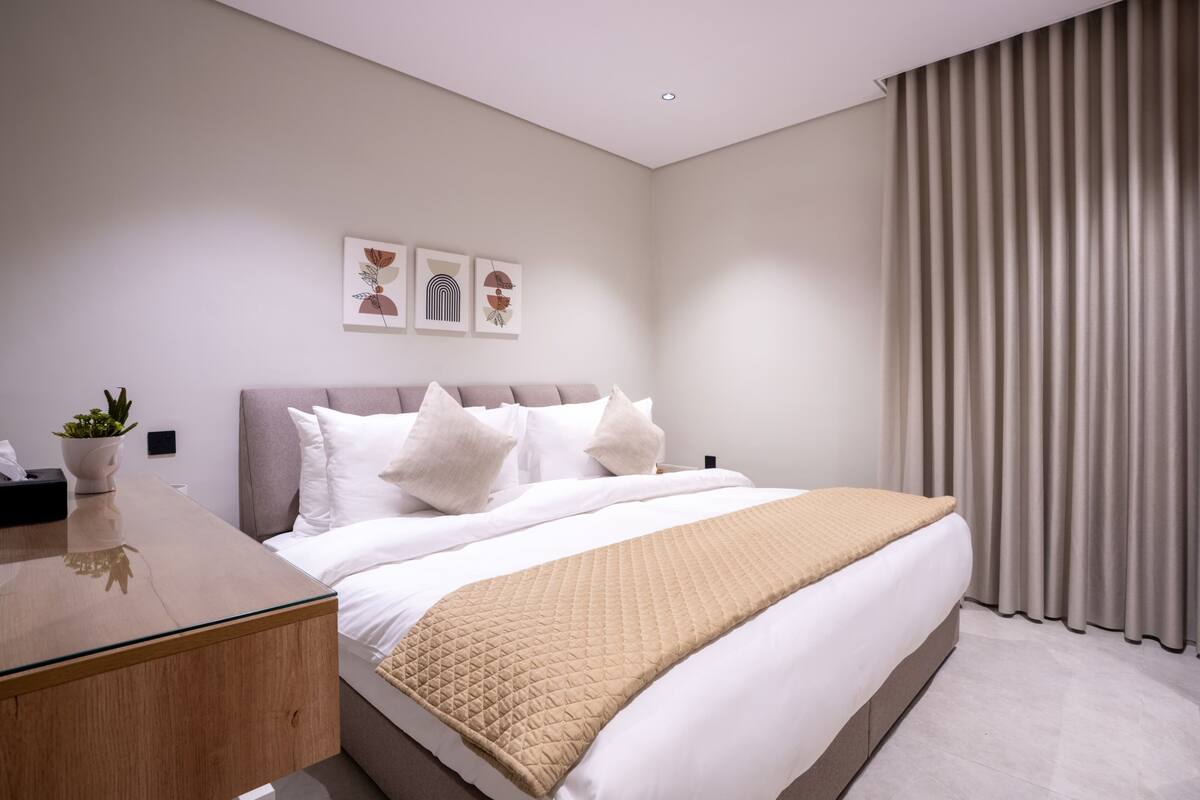 Um quarto moderno com cama, mesa de cabeceira e um vaso de planta.