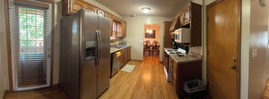 Une cuisine équipée d’un réfrigérateur, d’une cuisinière, d’un four à micro-ondes et de meubles de rangement en bois.