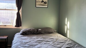 A bedroom with a bed, a window with curtains, a framed picture on the wall, and a small table. - Charming 2-bedroom Getaway in Broadus (Broadus)