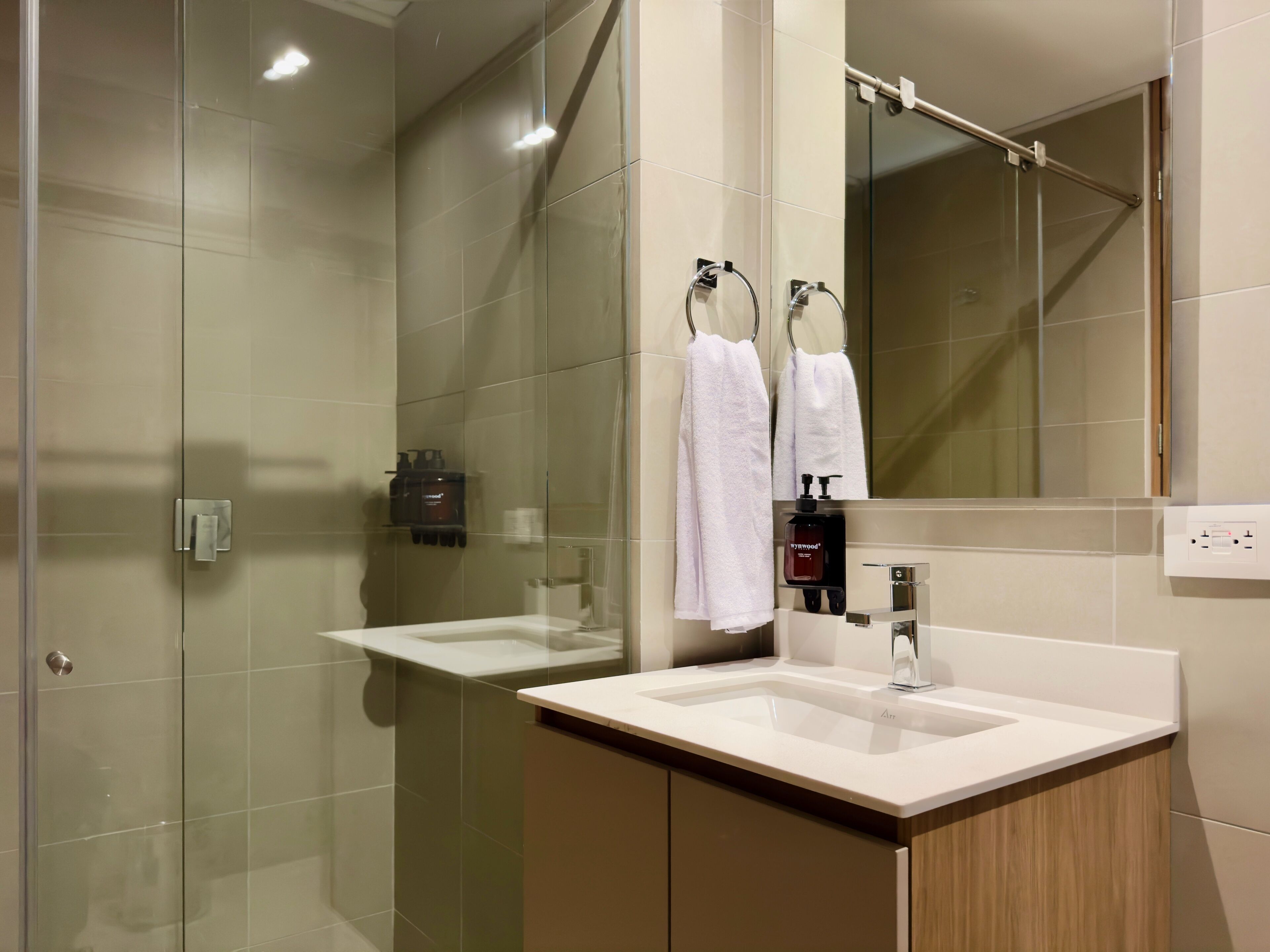 Ein modernes Badezimmer mit zwei Waschbecken, einer Duschkabine aus Glas und einem großen Spiegel.