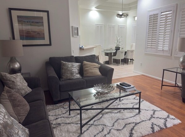 A living room with a dark grey sofa, a glass coffee table, and a white patterned rug. - TPC golf course North Scottsdale. (Scottsdale)