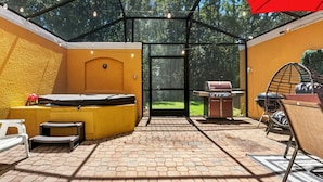 Ein überdachter Patio-Bereich mit Whirlpool, Grill und Sitzgelegenheiten.