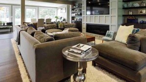 A spacious living room with a large sectional sofa, a flat-screen TV, and built-in shelving.