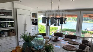 A modern kitchen with a marble countertop, a large fish tank, and a dining area with a view of a lake.