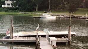 A dock with a boat, a wooden pier, and a house in the background.