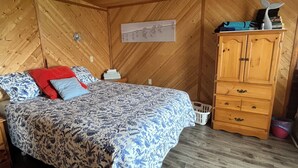 Une chambre à coucher avec un lit, une armoire en bois et un ventilateur de plafond.