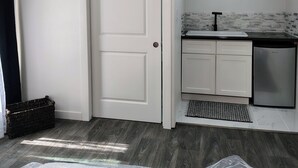 A modern kitchen with white cabinetry, a built-in dishwasher, and a tiled backsplash. - Welcoming studio in Roseville perfect for a cozy getaway (Roseville)