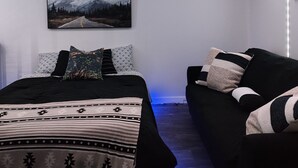 A bedroom with a bed, a couch, a painting of a mountain road, and LED strip lighting. - Welcoming studio in Roseville perfect for a cozy getaway (Roseville)