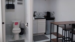 A compact kitchen with a sink, stove, and white cabinets. - Welcoming studio in Roseville perfect for a cozy getaway (Roseville)