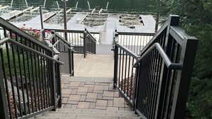 Una escalera que conduce a un muelle, con un lago y un bosque al fondo.