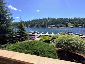 A lakeside view with docked boats, a wooden deck, and dense forest in the background.