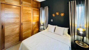 A bedroom with a bed, wooden wardrobe, ceiling fan, wall sconces, curtains, and decorative sunflowers.