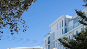 Une personne sur une planche à roulettes devant un bâtiment moderne à plusieurs étages, doté de balcons.