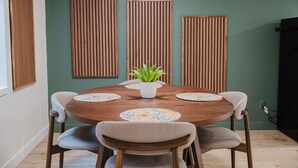 A dining area with a round wooden table, four chairs, and a potted plant in the center. - NEW Spacious Park-view Walk-out Basement near Coffee and Trails (Colorado Springs)