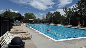 A swimming pool with lounge chairs and a trash can. - NEW Spacious Park-view Walk-out Basement near Coffee and Trails (Colorado Springs)