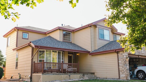 A two-story house with a front porch, a garage, and a stone foundation. - NEW Spacious Park-view Walk-out Basement near Coffee and Trails (Colorado Springs)