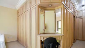 A room with a large wooden wardrobe, a desk with a chair, and a mirror. - Casa Liberdade (São Paulo)