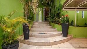 A set of outdoor stone steps leading to a covered entrance, surrounded by lush greenery and potted plants. - Casa Liberdade (São Paulo)