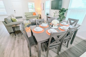 Comedor con mesa de madera dispuesta para cuatro personas, rodeada de sillas grises.