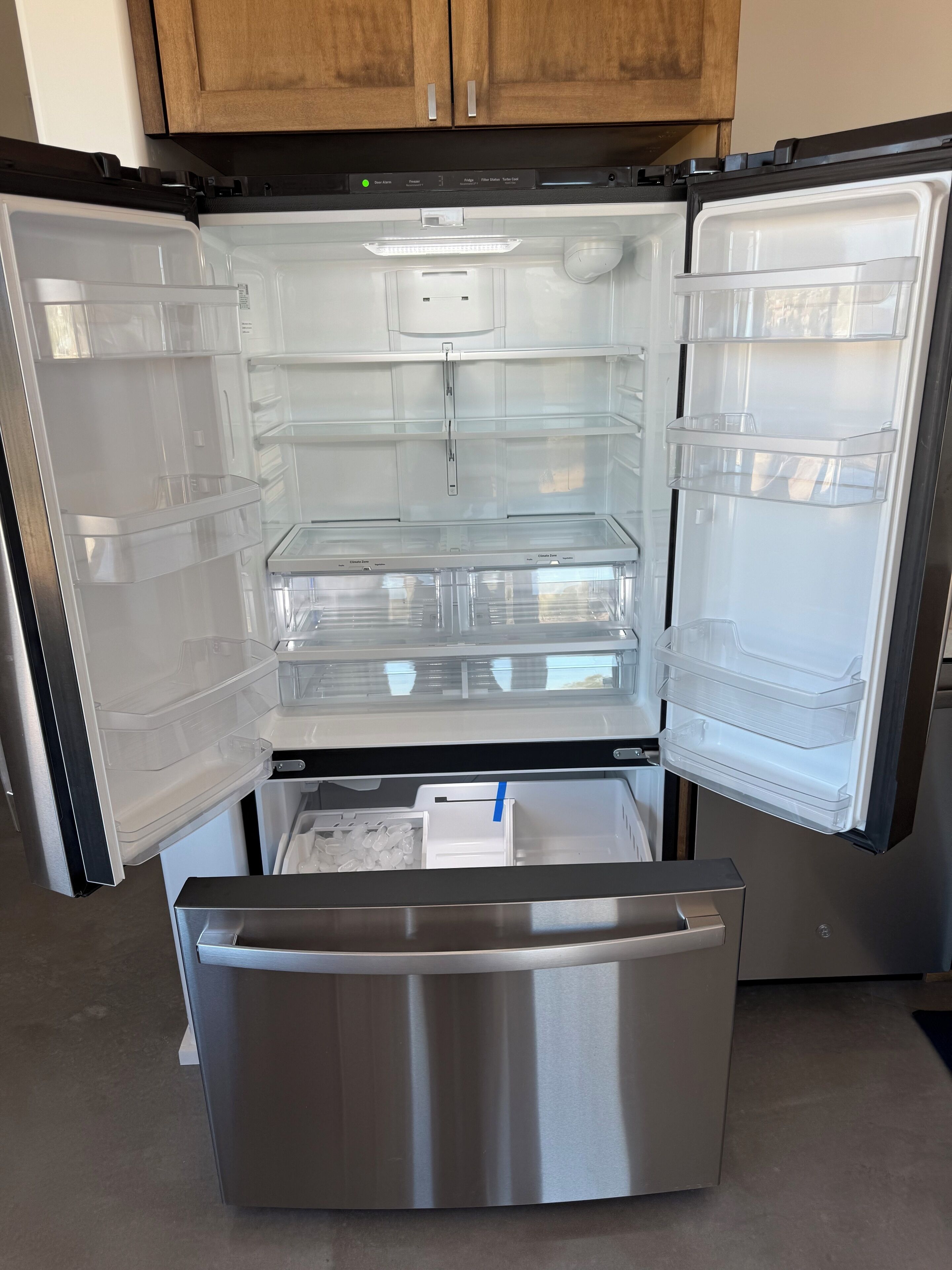 Un réfrigérateur ouvert, doté de bacs de rangement transparents et d’un tiroir congélateur.